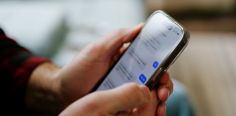 Persona controlla con attenzione una conversazione SMS su smartphone per capire se si tratta di smishing
