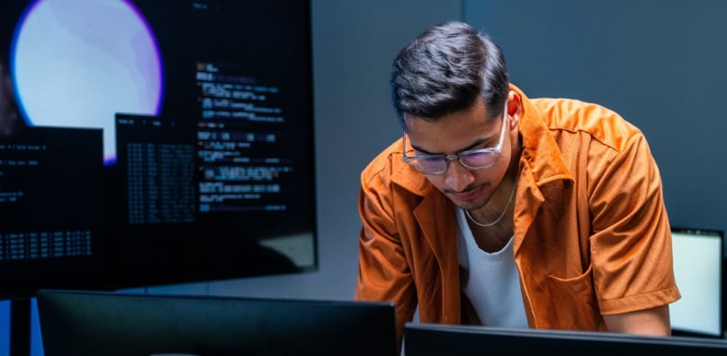 Professionista analizza schermate di codice al computer per prevenire i costi di un data breach