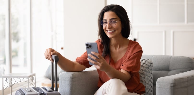 Persona in viaggio con smartphone in mano, sicurezza informatica in vacanza