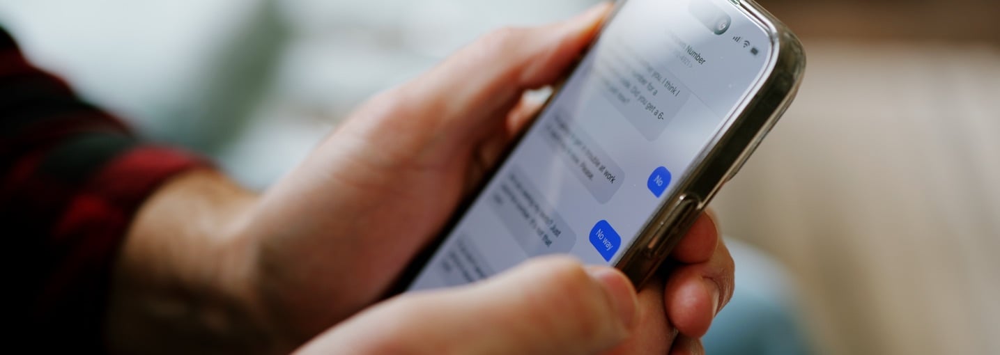Persona controlla con attenzione una conversazione SMS su smartphone per capire se si tratta di smishing