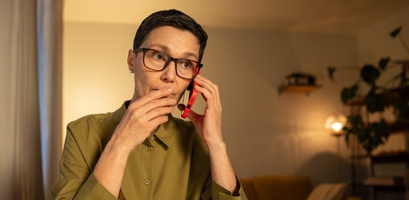 Persona al telefono con espressione dubbiosa, truffa telefonica vishing