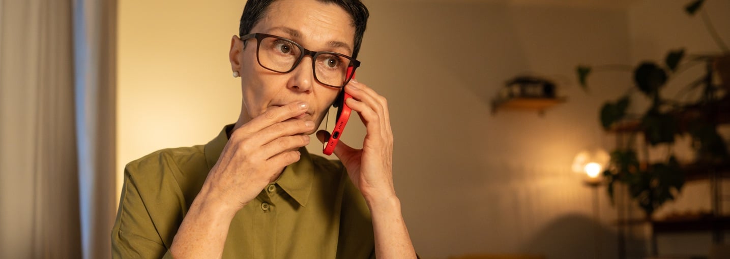 Persona al telefono con espressione dubbiosa, truffa telefonica vishing