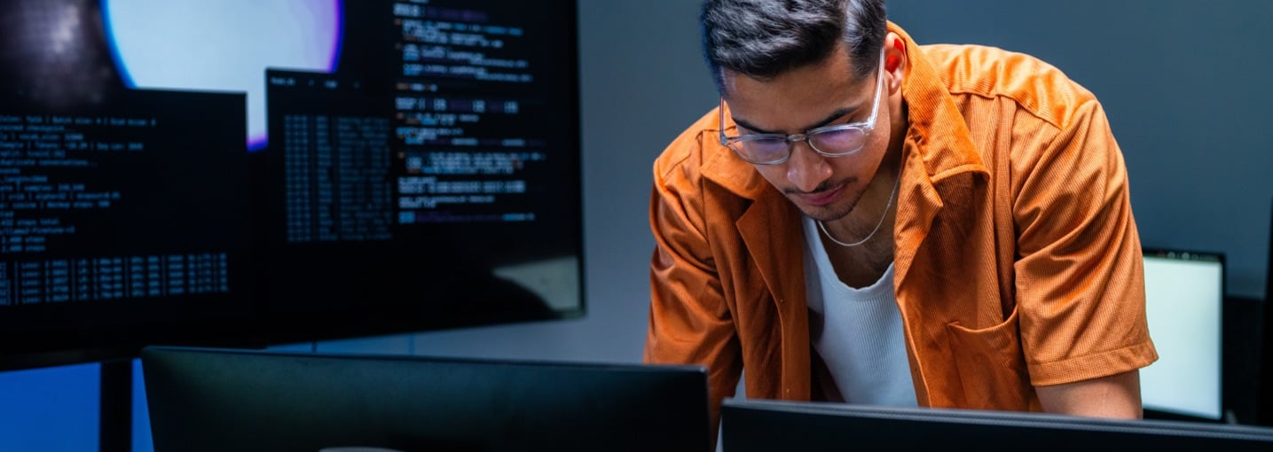 Professionista analizza schermate di codice al computer per prevenire i costi di un data breach