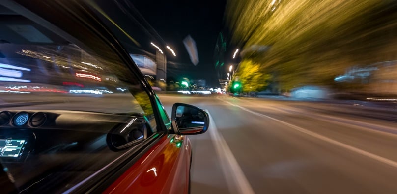 Auto in corsa ad alta velocità di notte in città, situazione tipica di un incidente con auto pirata.