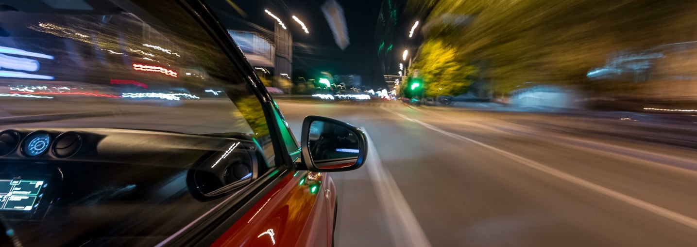 Auto in corsa ad alta velocità di notte in città, situazione tipica di un incidente con auto pirata.