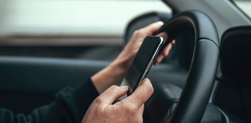 Guidatore distratto dallo smartphone al volante, una delle principali cause di incidenti stradali in aumento.