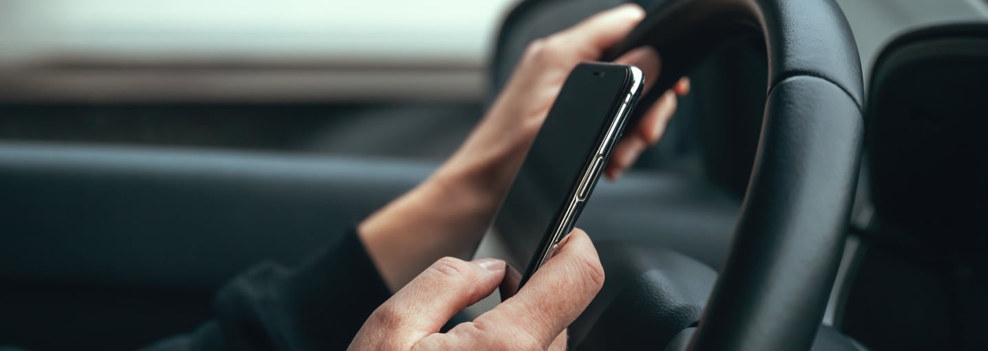 Guidatore distratto dallo smartphone al volante, una delle principali cause di incidenti stradali in aumento.