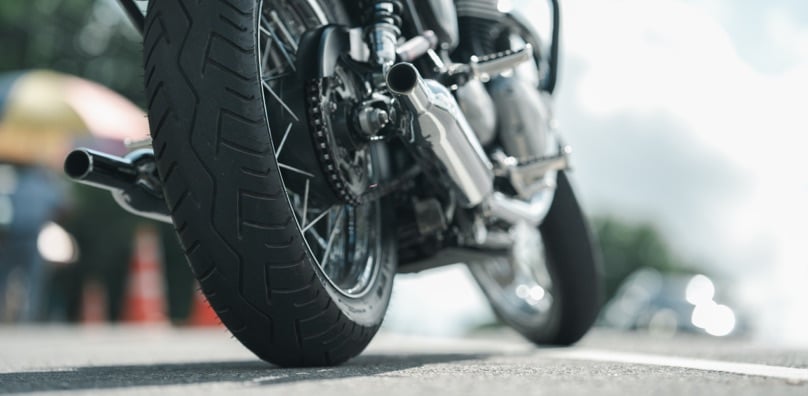 Dettaglio della ruota posteriore e dello scarico di una moto ferma su strada, pronta per la polizza moto.