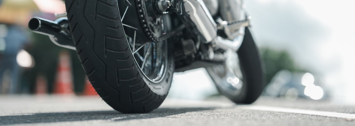 Dettaglio della ruota posteriore e dello scarico di una moto ferma su strada, pronta per la polizza moto.